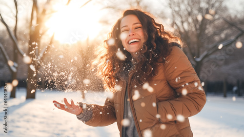 Fototapeta Smiling woman throwing snow in the air at sunny winter day. Winter concept.
