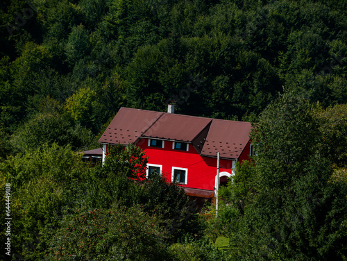 Modern red house in Carpathian mountains forest, Ukraine, Europe. Scenic landscape green meadow spruce trees sunny day Eco Local countryside tourism hiking trails Cottagecore Zakarpattya region travel