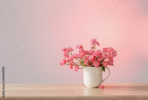 pink roses in ceramic vase on pink background