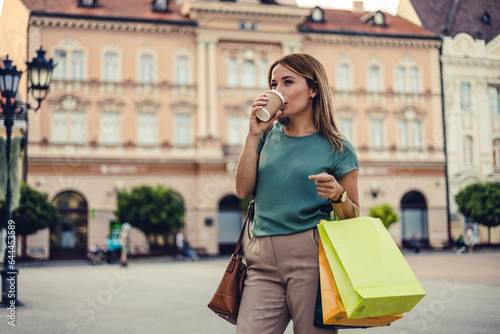 Attractive brunette woman with shopping bags walking on city streets.
