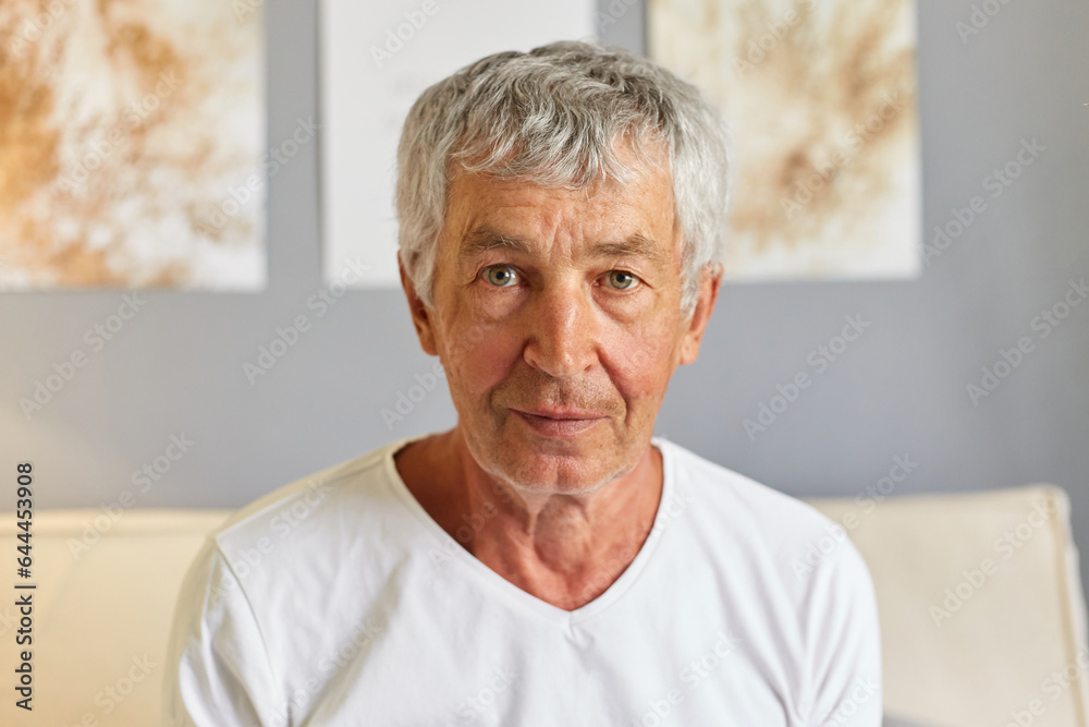 Portrait of masture older retired man looking at camera elderly grandfather with calm facial expression male wearing white T-shirt sitting on cough. Portrait of masture older retired man looking at camera elderly grandfather with calm facial expression male wearing white T-shirt sitting on cough.