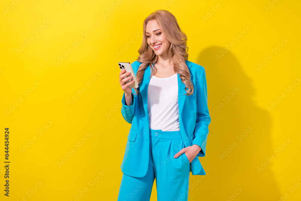 Photo of gorgeous positive person use smart phone texting typing blog post isolated on yellow color background Photo of gorgeous positive person use smart phone texting typing blog post isolated on yellow color background