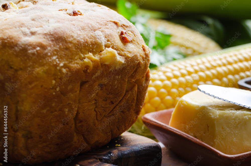 Zoomed view at homemade loaf of cornbread on wooden kitchen table. Cobs and butte aside