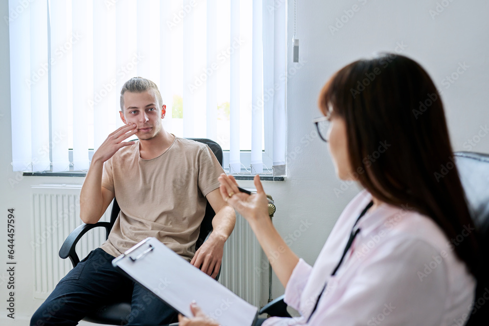 Young male student at therapy meeting with college psychologist counselor Young male student at therapy meeting with college psychologist counselor