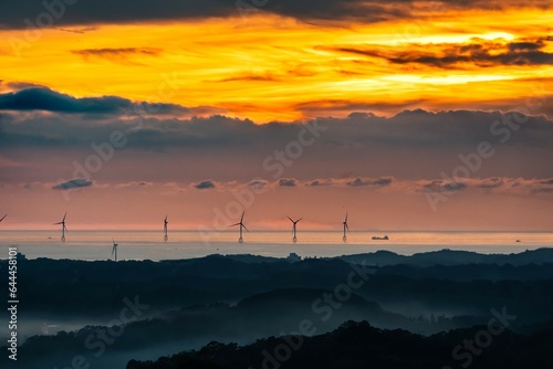 sunset over the ocean wind power farm