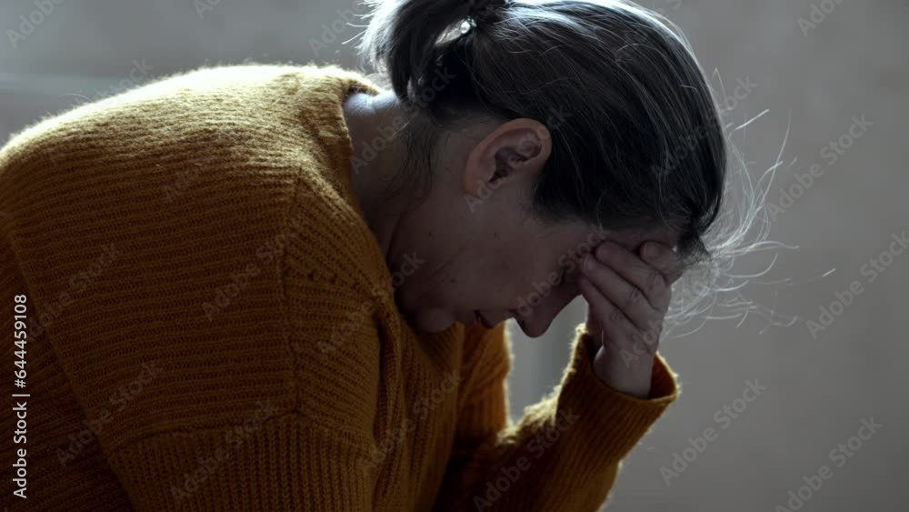 Mature woman struggles from mental bad health at home. Senior lady cries sitting at home. Grey-haired female suffers with depression
