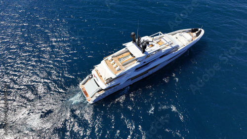 Aerial drone photo of beautiful modern super yacht with wooden deck cruising in low speed deep blue Aegean sea