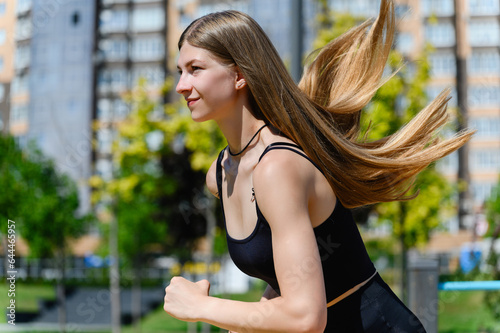 Young beautiful woman with long hair running outdoors at the city park.