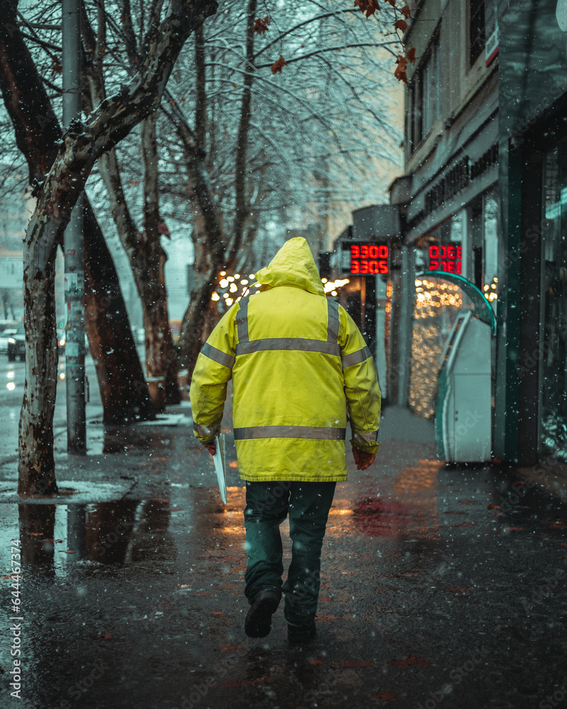 Obraz premium The man in the yellow jacket is walking on the street