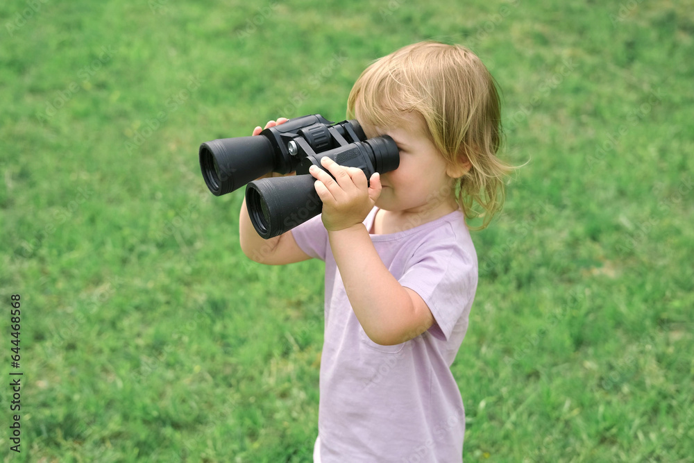 Little girl using binoculars in a forest. 2 years kid looking ahead. Smiling baby with spyglass. Adventure, Imagination, travel concept. Freedom, vacation. Happy child playing outdoor in summer field Little girl using binoculars in a forest. 2 years kid looking ahead. Smiling baby with spyglass. Adventure, Imagination, travel concept. Freedom, vacation. Happy child playing outdoor in summer field