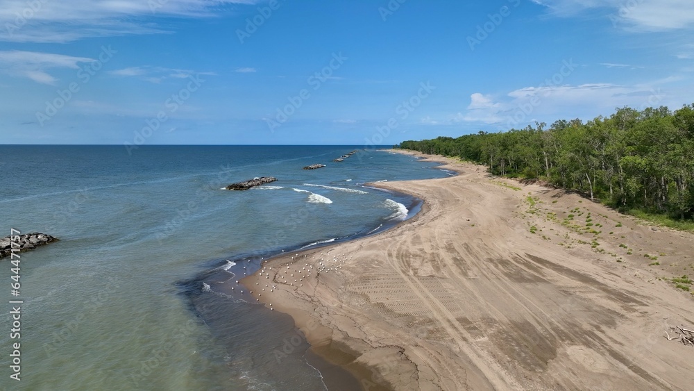 Beautiful sandy beach and coastline of barrier island on Lake Erie Pennsylvania Presque Isle State Park with nature preserve in sunshine on summer day with blue sky and calm waves and surf