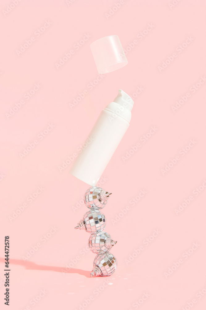 Bottle of cosmetic cream with festive decor on a pink background. Sale concept