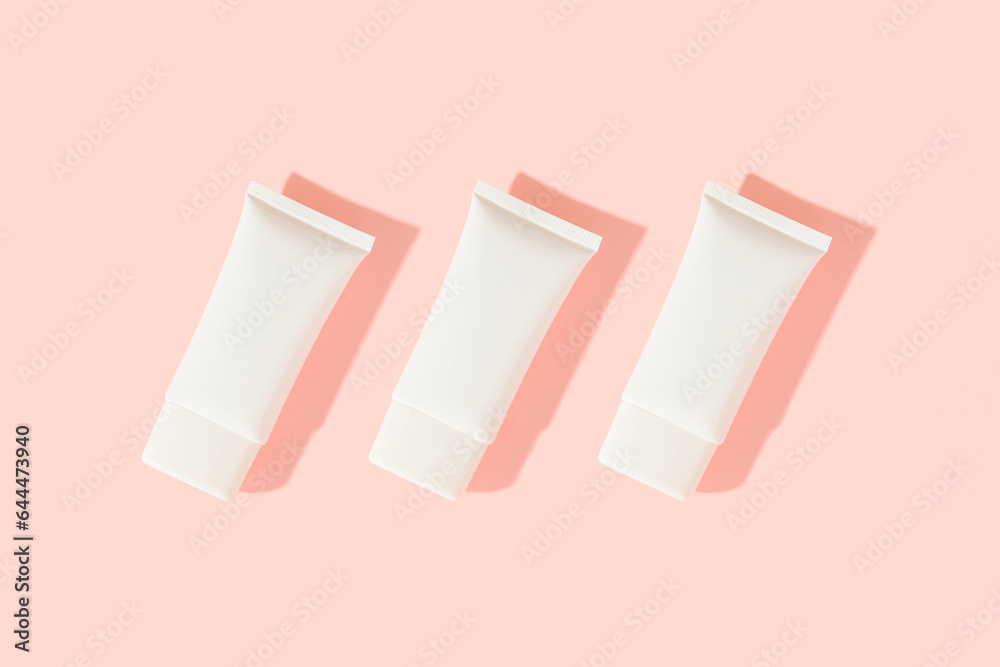 Three white plastic cosmetic tube on pink background. Cosmetics sale concept Three white plastic cosmetic tube on pink background. Cosmetics sale concept