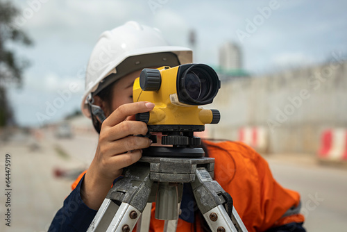 Professional female engineer surveyor takes measures with theodolite at road construction site.