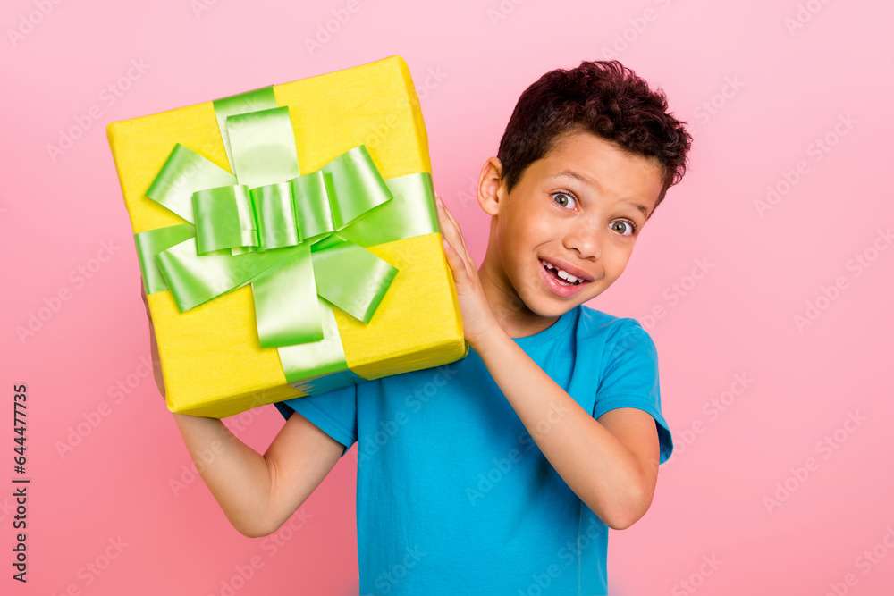 Photo of excited cheerful small boy wear blue t-shirt getting huge gift package isolated pink color background Photo of excited cheerful small boy wear blue t-shirt getting huge gift package isolated pink color background