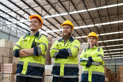 Portrait of group of man and woman workers working at wood pallet factory. Team carpenter in uniform with helmet safety smile and standing arms crossed look at camera in wood warehouse. © Supachai