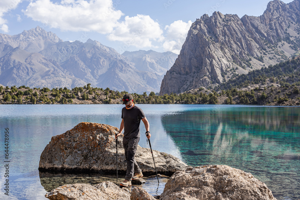 Man hiker exploring mountains lake in Tajikistan Man hiker exploring mountains lake in Tajikistan