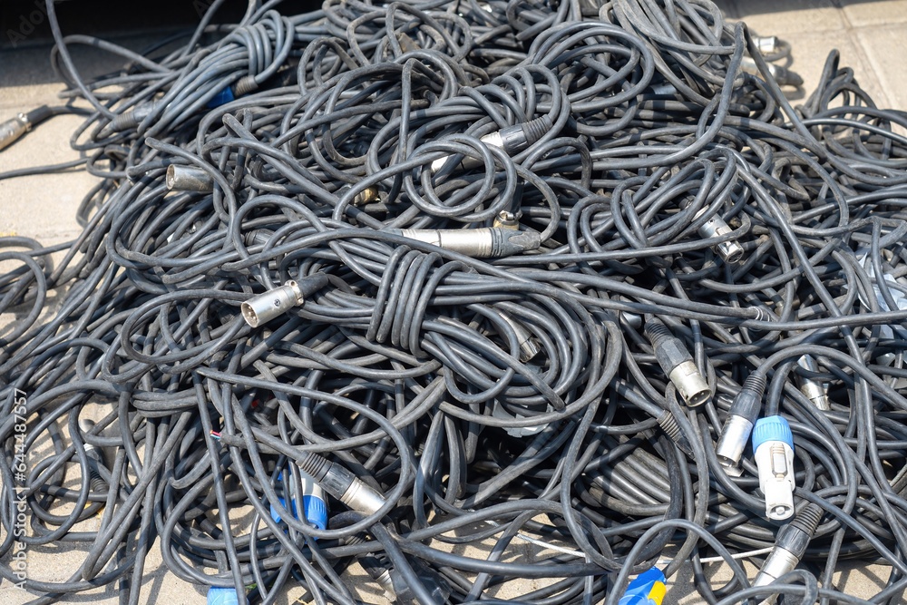 Wires from audio equipment. Tangled cables. Wires for concert equipment. Cable for lighting fixtures on ground. Tangled wires for electrical equipment. Cables for mounting concert stage