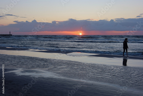 Single woman silhouette. Scenic sunset over the sea. Baltic sea after the rainy day. Poland seaside, Leba village and beach. Seascape