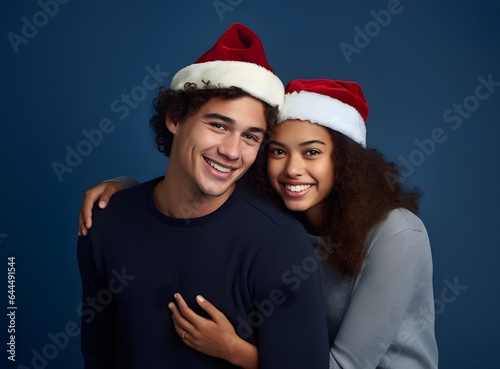 Merry young international couple  Caucasian man and African American woman with Christmas Santa hats hugging  posing isolated on plain pastel light pink  blue background Happy New Year 2023 holiday 
