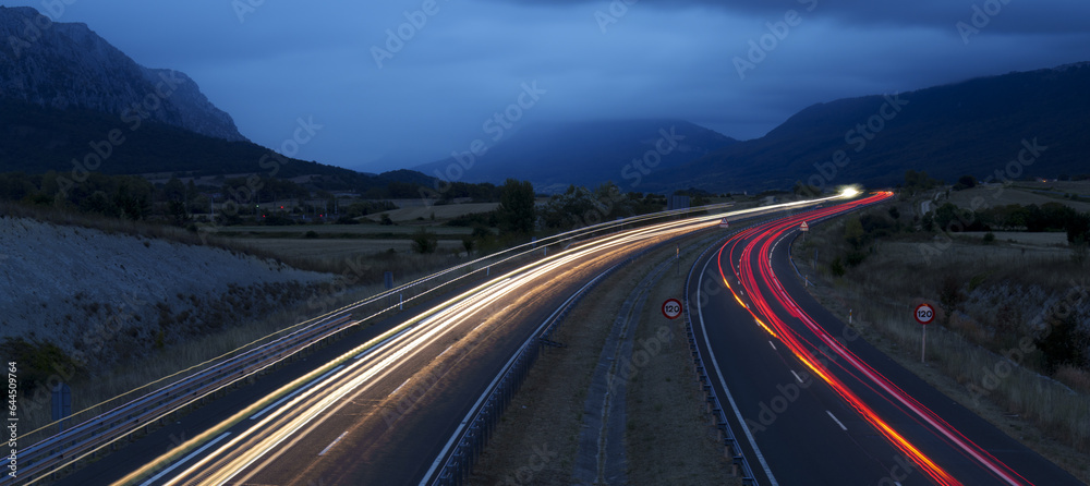 cars driving on the freeway with lights on at dusk
