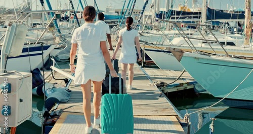 Boat port, suitcase and back of people walking to travel, vacation and summer trip at ocean. Luggage, pier and crew at ship dock, luxury holiday of tourist and outdoor on wood bridge at yacht at sea photo