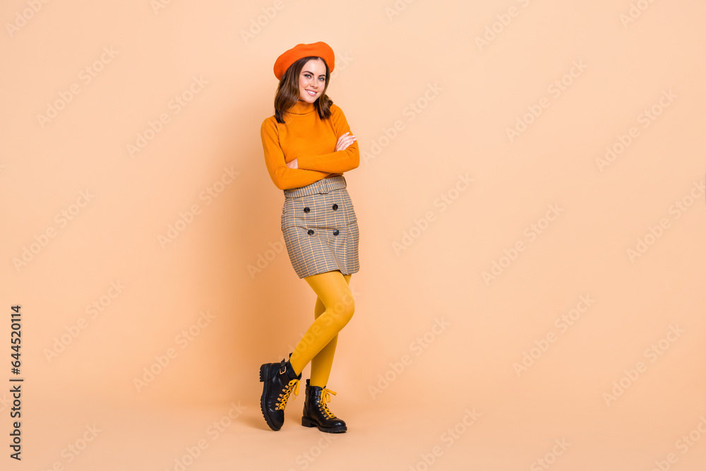 Full length photo of cheerful adorable person crossed arms empty space isolated on beige color background Full length photo of cheerful adorable person crossed arms empty space isolated on beige color background