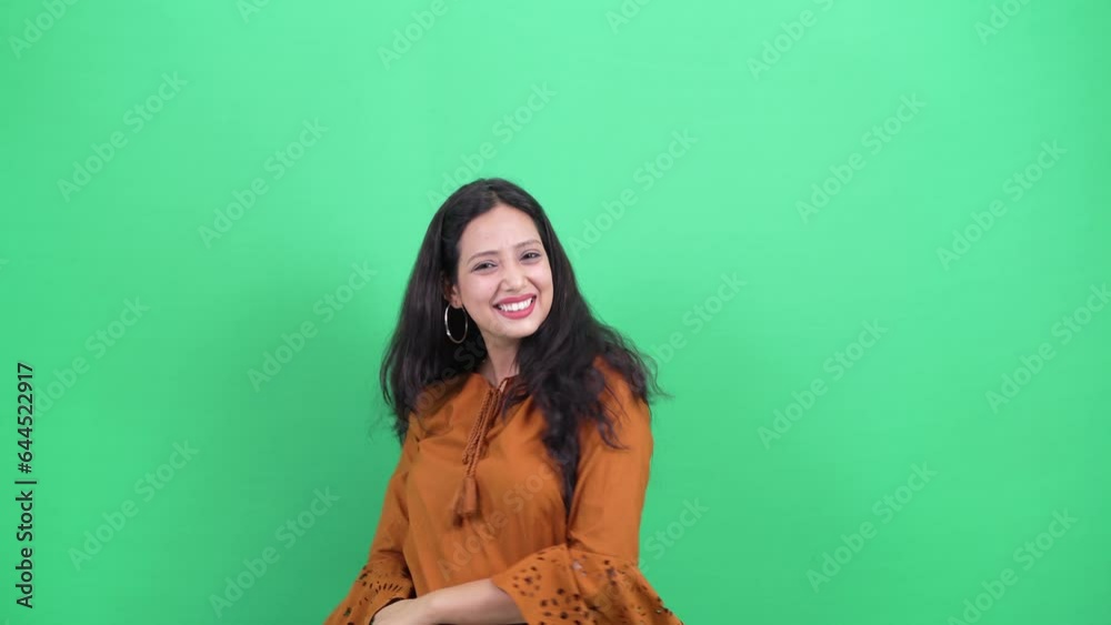 Beautiful Young indian woman casually dressed jumping in to camera from bottom, excited shaking hands saying hello with happy and excited gesture on green screen chroma background. Beautiful Young indian woman casually dressed jumping in to camera from bottom, excited shaking hands saying hello with happy and excited gesture on green screen chroma background.