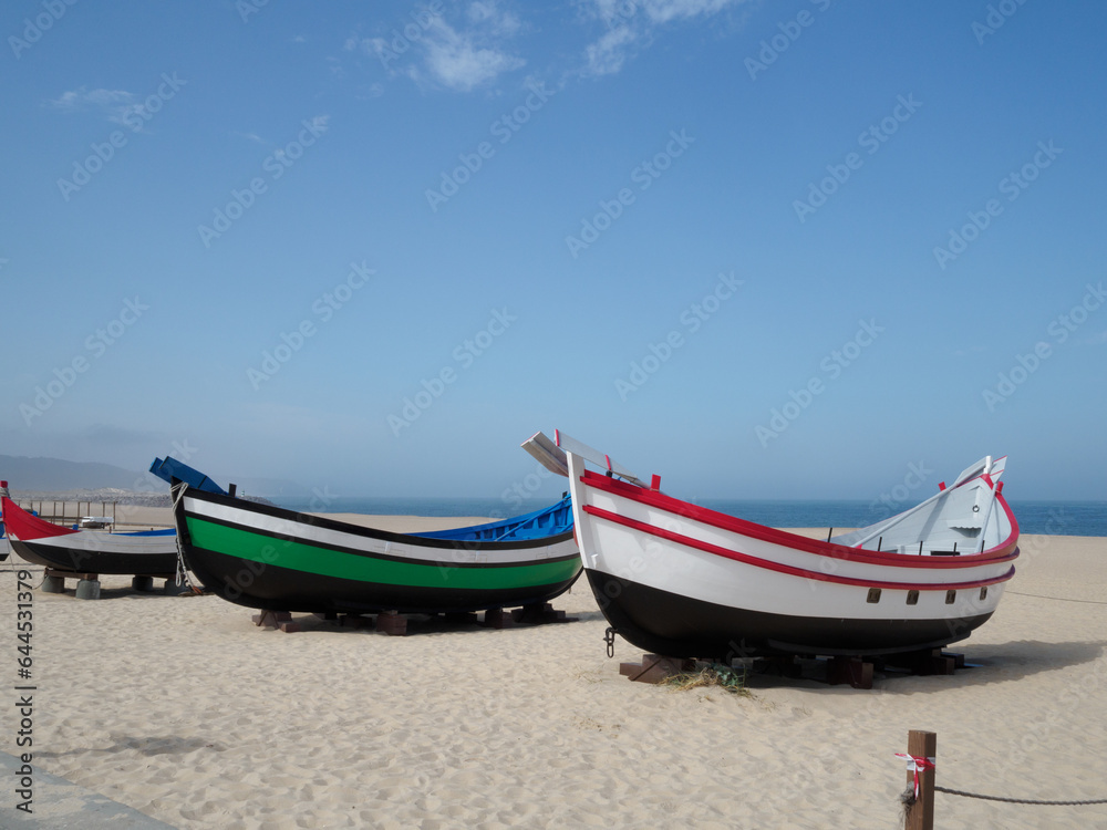 sets of two antique fishing boats on the beach of Nazaré, Portugal. Restored painting. nice sunny day with the sea in the background. sets of two antique fishing boats on the beach of Nazaré, Portugal. Restored painting. nice sunny day with the sea in the background.
