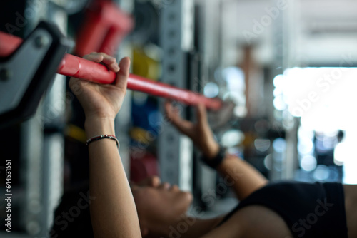 Close up, fitness girl lifting barbell weights at the gym, doing exercises with barbell, fitness muscular body, selective focus