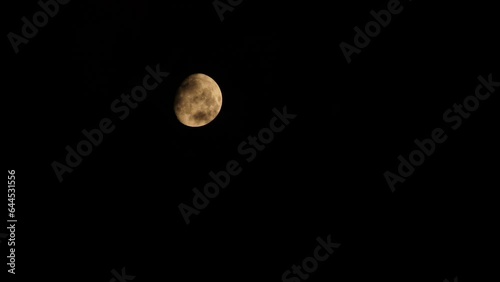 Clear moon. Black clouds. Black clouds float against the backdrop of the yellow moon with craters. The partly clear moon is setting down. 4k footage video. Close-up. Natural satellite of Earth