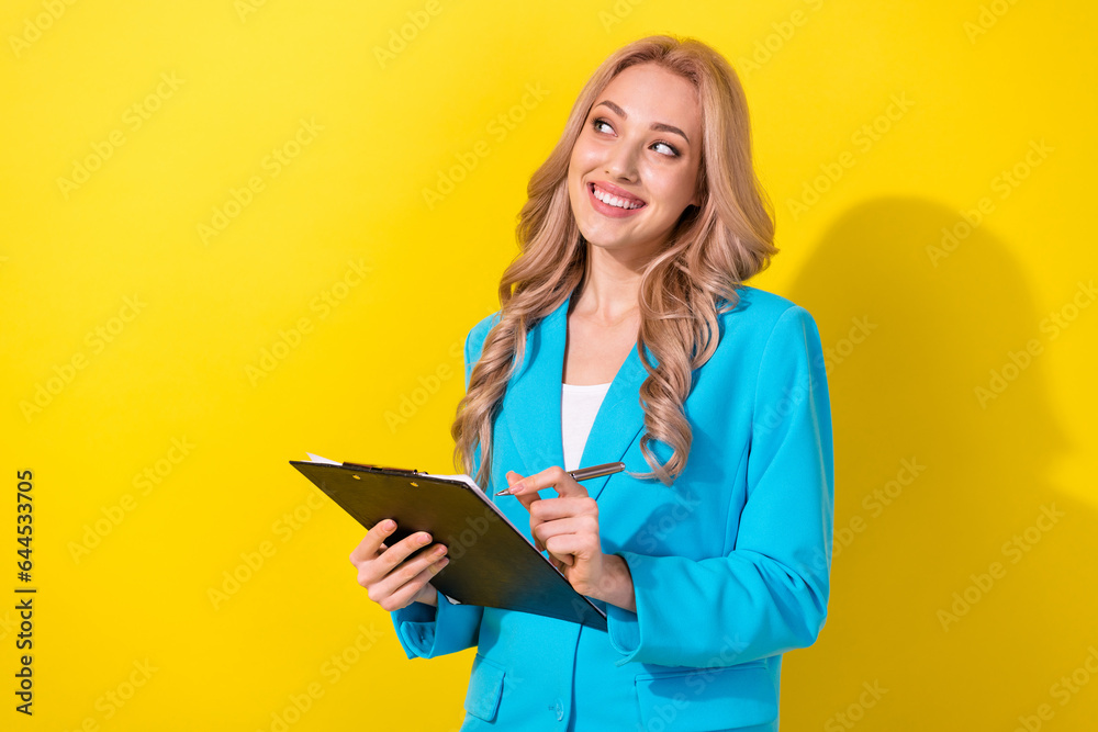 Photo of classy pretty corporate girl hold clipboard pen look empty space isolated on yellow color background Photo of classy pretty corporate girl hold clipboard pen look empty space isolated on yellow color background