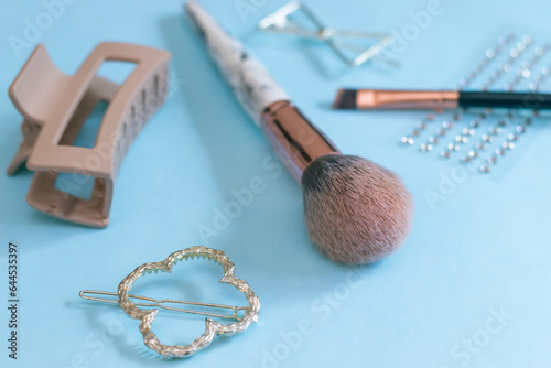 Makeup brushes, Makeup Essentials, hair clips, accessories on Blue Background. Healthcare, cosmetics. Blank space for writing