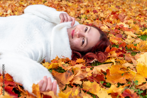 Woman portrait surrounded by autumn leaves. Woman sitting on the ground