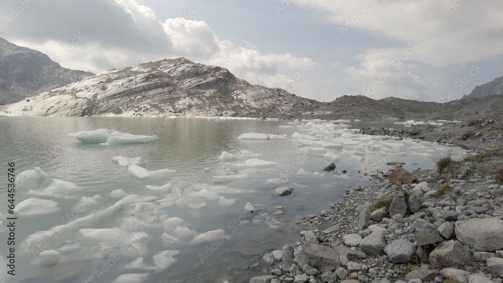 Block of ice in a mountain lake - icebergs break off from the melting glacier due to global warming - climate change and sea level rise due to high temperatures - Fellaria Glacier Italy, Europe