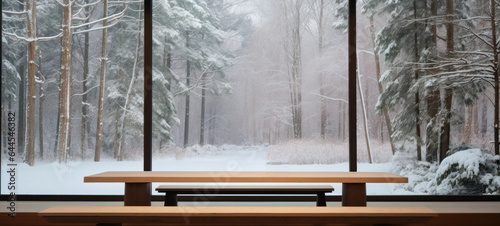  Empty wooden table with a modern large glass window in a snow-covered forest in the background with copy space, blank for text ads, and graphic design. © chiew