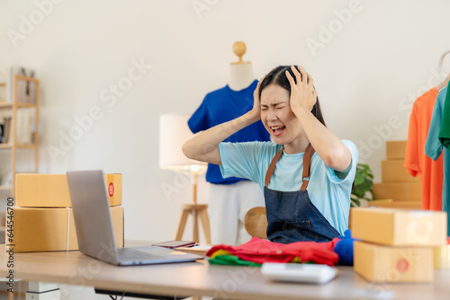 Young Asian woman working at small business ecommerce using laptop stressed and frustrated surprised and angry face. Small online business owner Asian woman stressed headache with parcel box at home.
