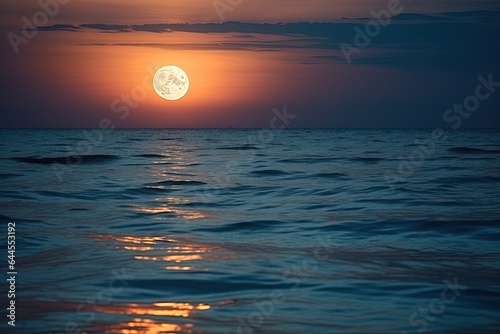 A large full red moon over ocean horizon with reflection on the water 