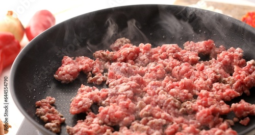 Raw Minced meat is fried in a pan with steam. Cooking bolognese sauce. Food preparation in the kitchen. A series of photos to visualize the recipe.