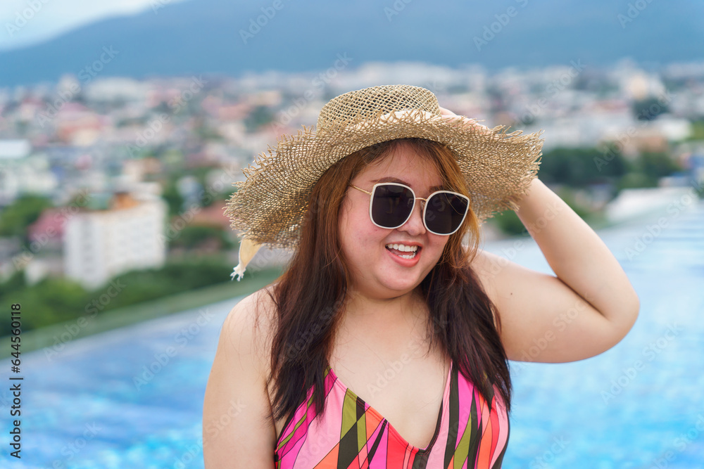 Overweight young asian woman wearing orange swimsuit and straw beach sun hat relaxing in pool Happy plus size woman cheery funny Vacation Traveling in summer. Overweight young asian woman wearing orange swimsuit and straw beach sun hat relaxing in pool Happy plus size woman cheery funny Vacation Traveling in summer.
