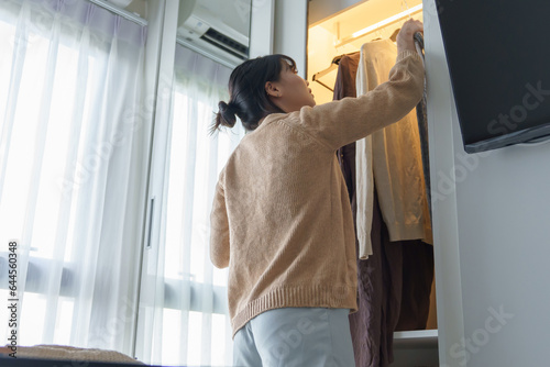 Asian girl preparing vacation choosing clothes with wardrobe in bedroom before holidays trip