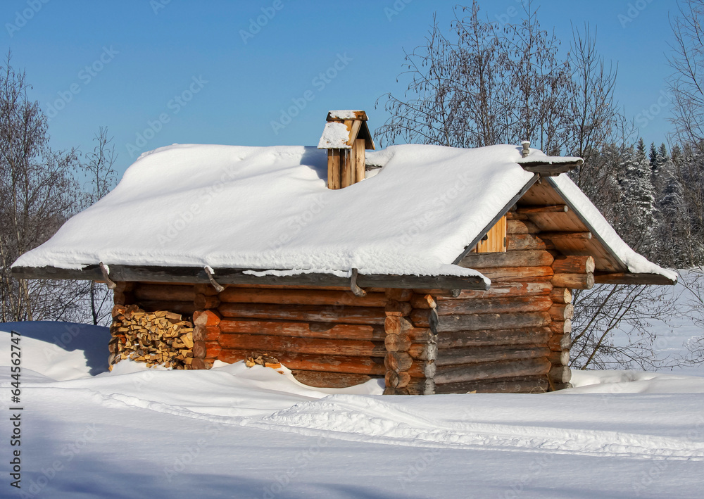 Russian typical rural log sauna near pond covered with ice and snow.