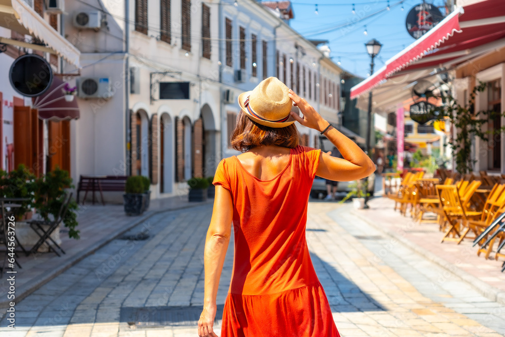 Tourist woman in red dress enjoying vacation walking on the streets of Shkoder city. Albania
