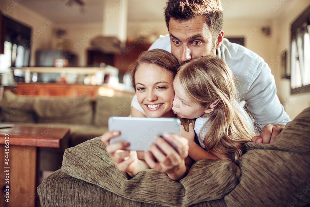 Young family using the smartphone on the couch in the living room at home Young family using the smartphone on the couch in the living room at home