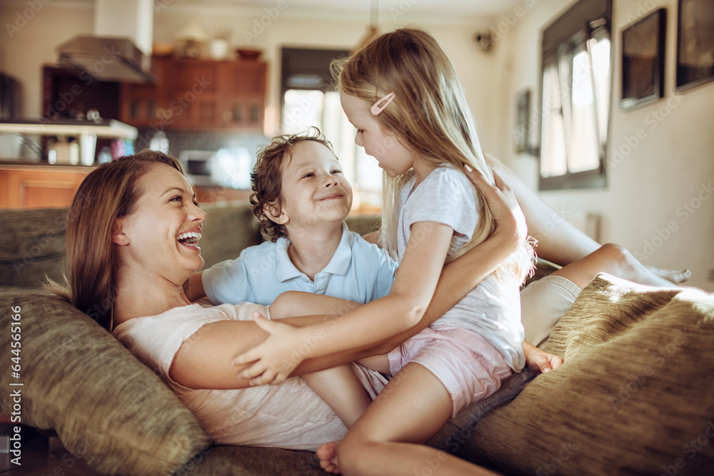 Young mother playing with her children on the couch in the living room at home Young mother playing with her children on the couch in the living room at home