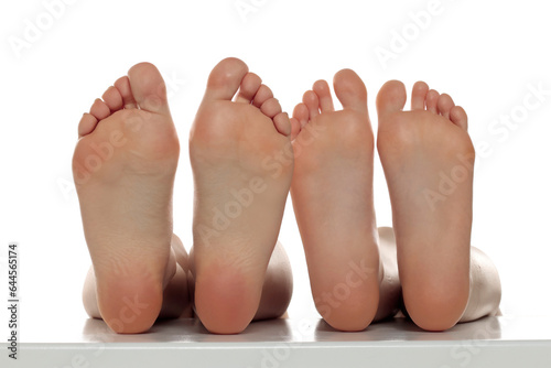 Two pairs od a beautiful well-groomed women's sole feet close-up on a white isolated background, The concept of foot skin care