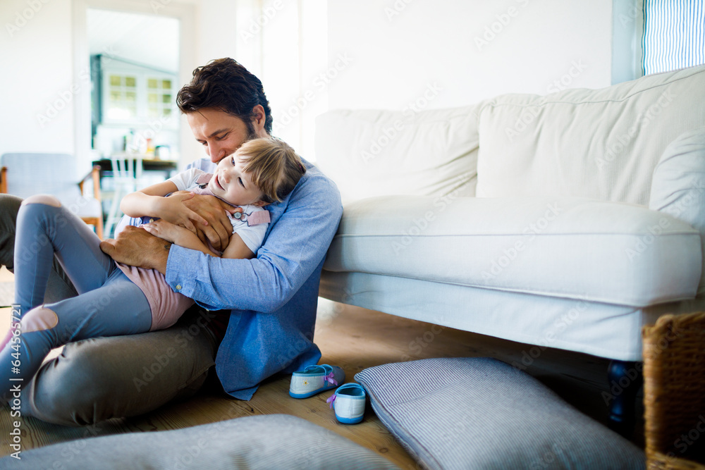Young father playing with his daughter in the living room at home