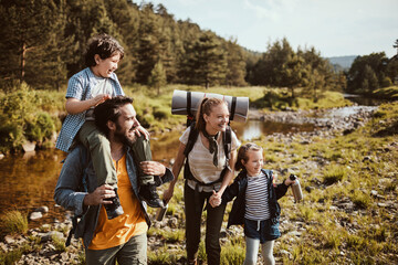 Young family crossing a creek while hiking in the forest and mountains