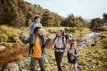 Young family crossing a creek while hiking in the forest and mountains