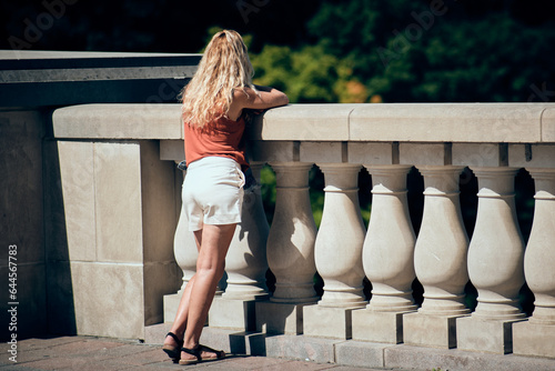 Mujer mirando el paisaje en un balcón de piedra